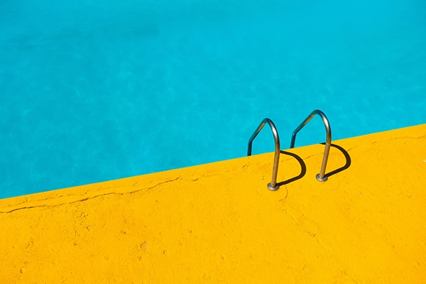 Blick in einen türkisen Pool von einem gelben Beckenrand aus als Beispiel für den Warm-Kalt-Kontrast